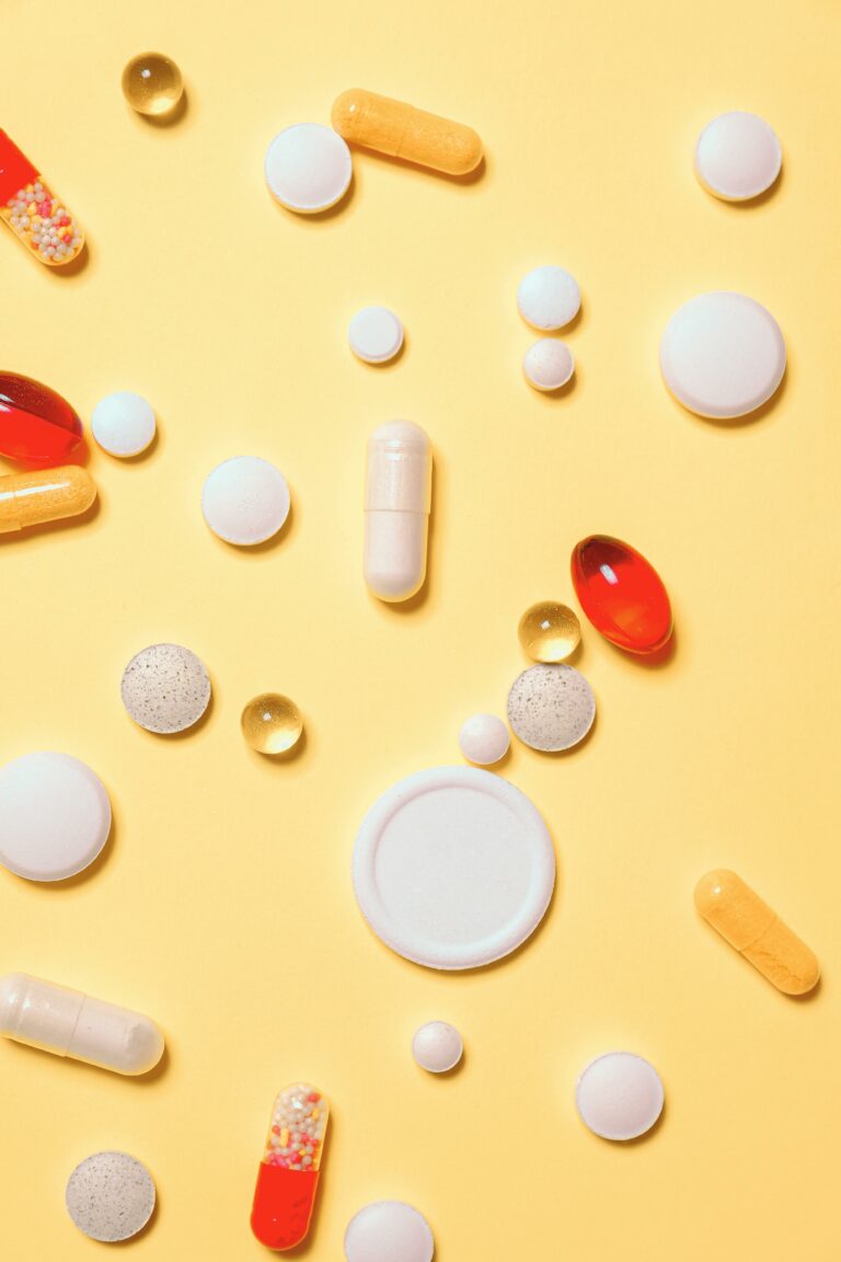 Varias pastillas y cápsulas sobre fondo amarillo, representando tratamientos médicos que podrían ser negados por prepagas