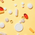 Varias pastillas y cápsulas sobre fondo amarillo, representando tratamientos médicos que podrían ser negados por prepagas